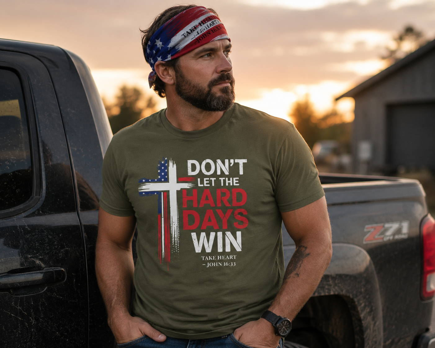 Outdoor lifestyle image of a man wearing the Don't Let the Hard Days Win faith-based t-shirt and Take Heart patriotic bandana near a pickup truck at sunset, symbolizing courage, resilience, and trust in God.