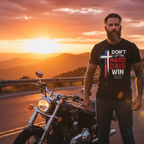 Bearded biker wearing Don't Let the Hard Days Win Tee Christian graphic t-shirt beside motorcycle at mountain sunset viewpoint
