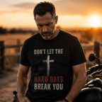 “Man wearing Don’t Let the Hard Days Break You black graphic tee beside motorcycle at sunset”