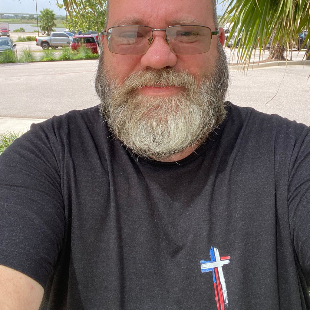 Shane, founder of Held & Anchored, wearing the Don't Let the Hard Days Win Tee — patriotic cross front design in Black Heather