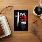 Christian encouragement postcard featuring a patriotic cross and “Don’t Let the Hard Days Win” message displayed on a wooden coffee table beside a Bible, coffee cup, glasses, and wooden cross.