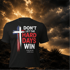 Black t-shirt with motivational quote and cross design against a dramatic sky background
