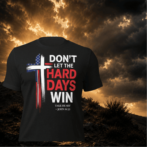 Black t-shirt with motivational quote and cross design against a dramatic sky background