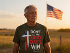 Man wearing Don't Let the Hard Days Win Tee in a field with American flag at sunset — Held & Anchored faith apparel