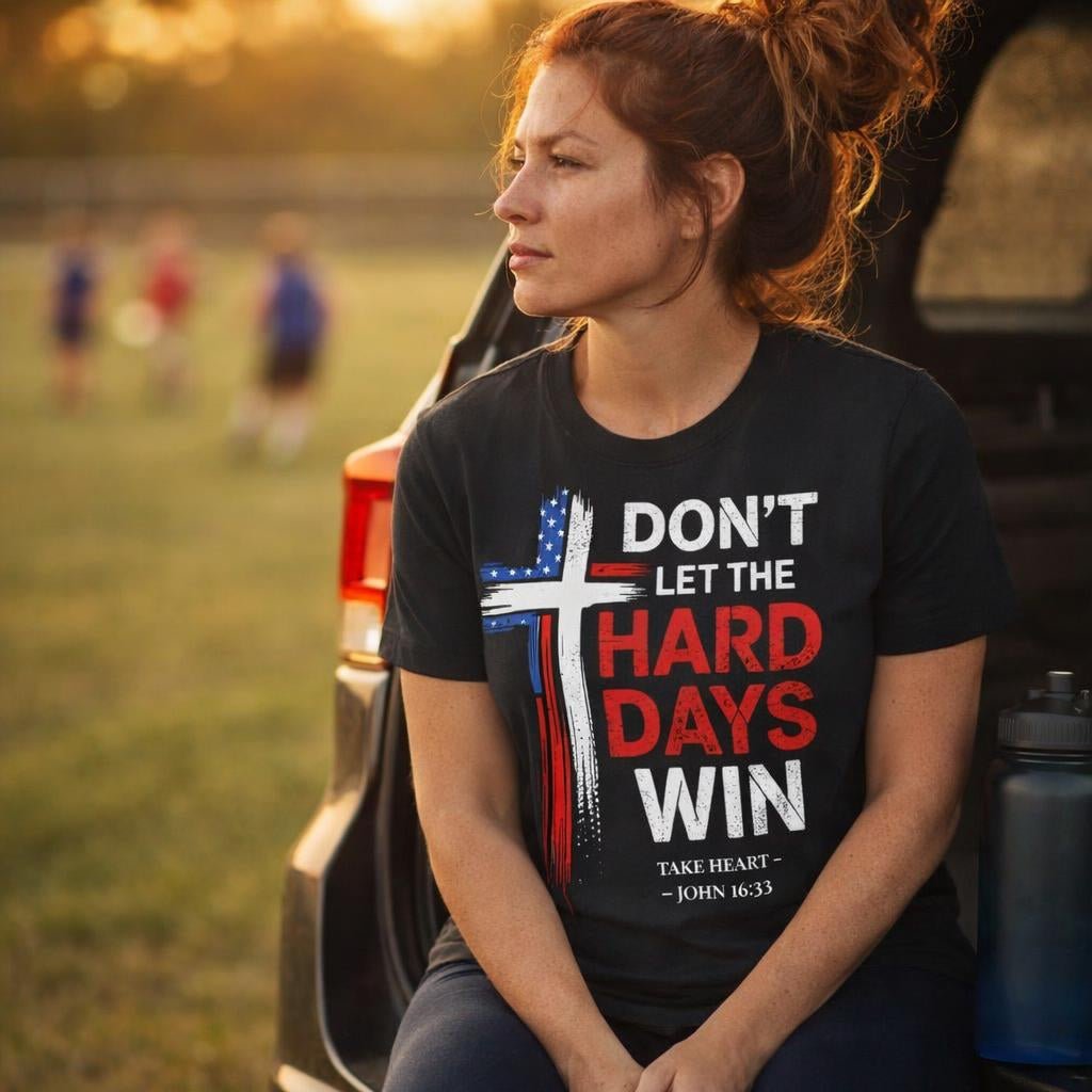Person wearing a t-shirt with a motivational message sitting outdoors near a vehicle.