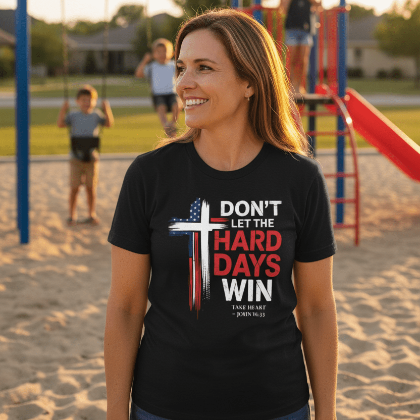 Woman wearing the “Don’t Let the Hard Days Win” patriotic Christian t-shirt at a playground during sunset with children playing in the background.