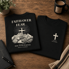 Folded Faith Over Fear Rider Tee showing front cross logo and mountain back print styled in a rugged faith-inspired flatlay setting.