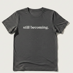 Black t-shirt with 'still becoming.' text on a light background