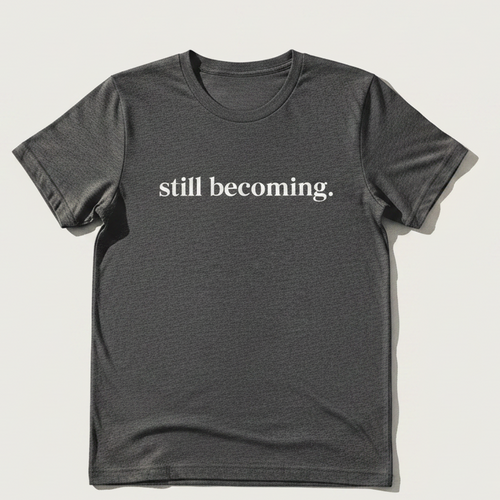 Black t-shirt with 'still becoming.' text on a light background