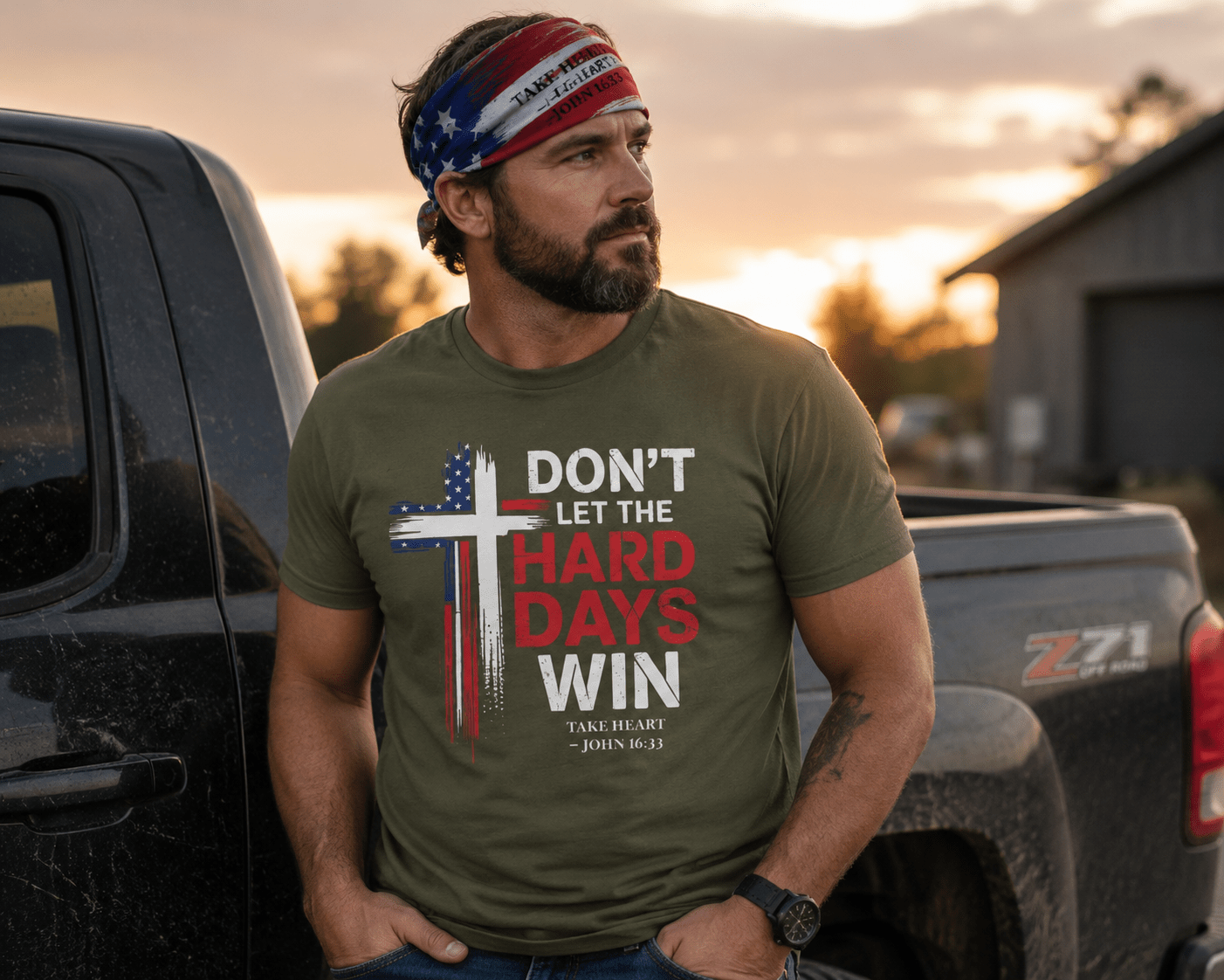 Outdoor lifestyle image of a man wearing the Don't Let the Hard Days Win faith-based t-shirt and Take Heart patriotic bandana near a pickup truck at sunset, symbolizing courage, resilience, and trust in God.