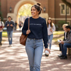 Person wearing a black sweatshirt with a logo on the front that says Still becoming.  Walking through a college campus.  
